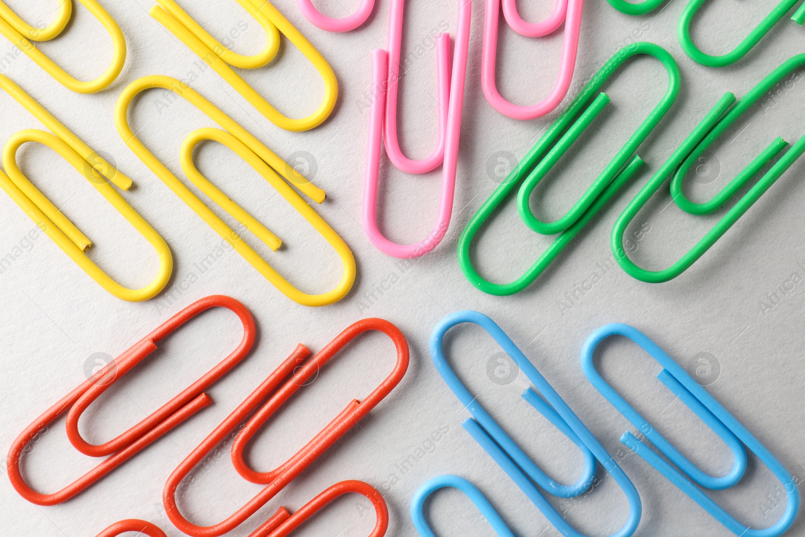 Photo of Colorful paper clips on light background, flat lay