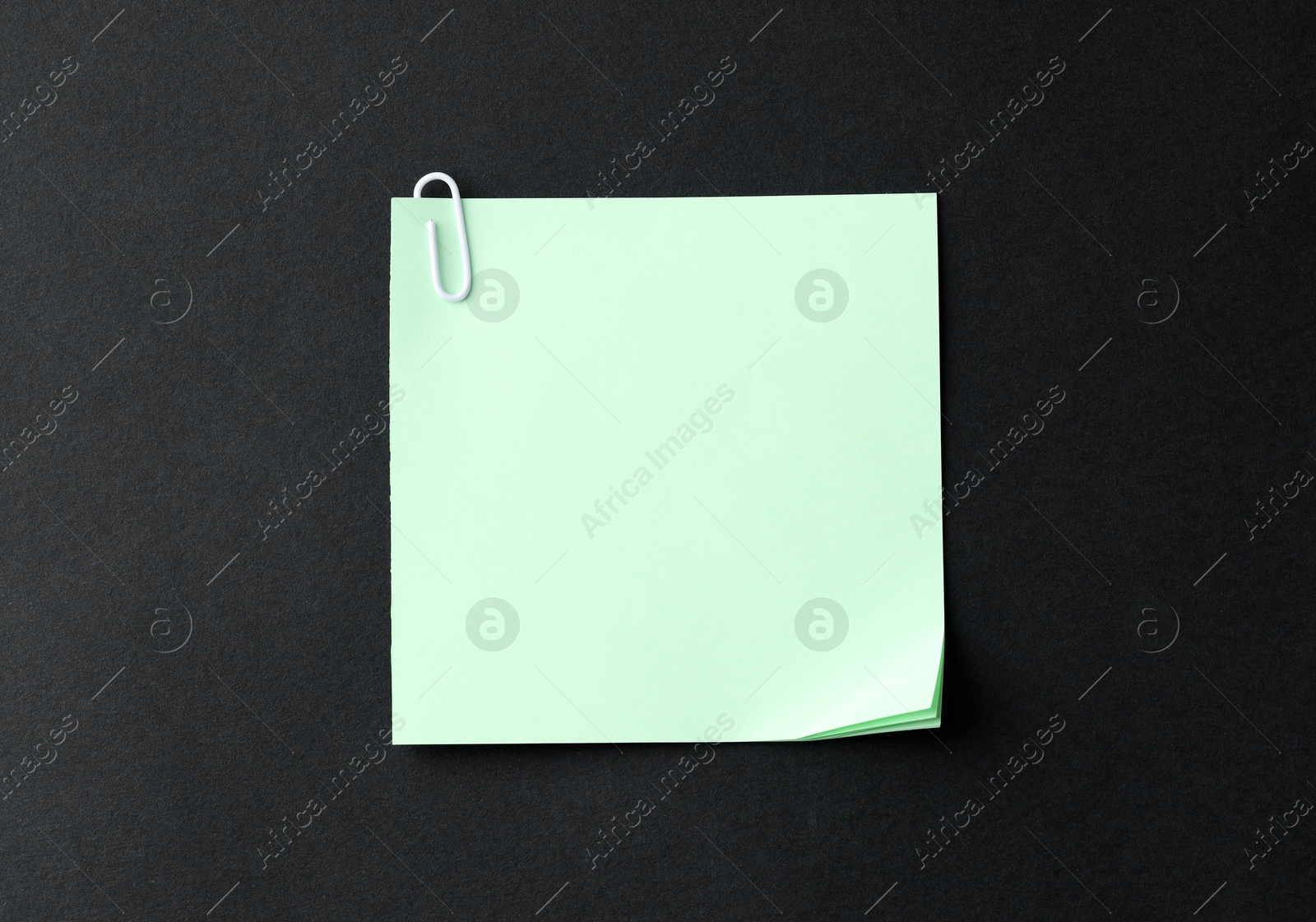 Photo of Paper notes with clip on black table, top view. Space for text