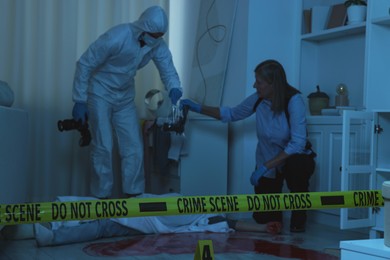 Photo of Forensic experts working at crime scene with dead woman's body indoors, selective focus