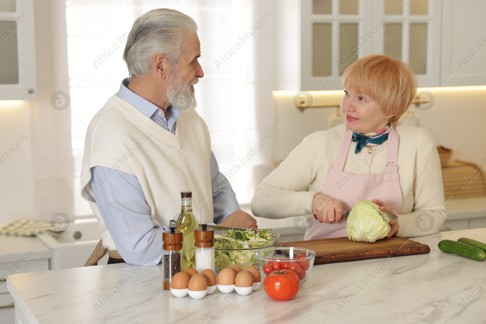 Photo of Senior couple cooking together at table in kitchen