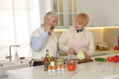 Photo of Senior couple cooking together at table in kitchen