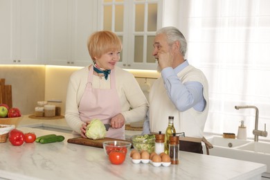 Senior couple cooking together at table in kitchen