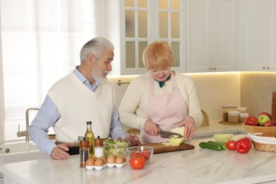 Photo of Senior couple cooking together at table in kitchen