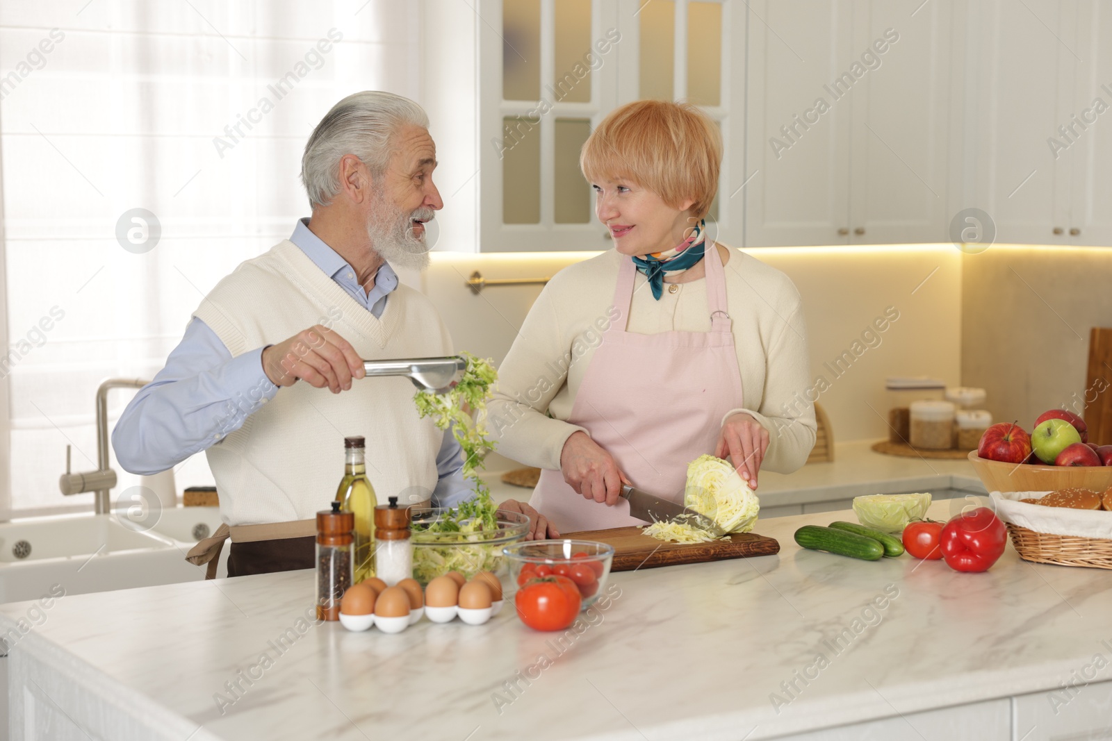 Photo of Senior couple cooking together at table in kitchen