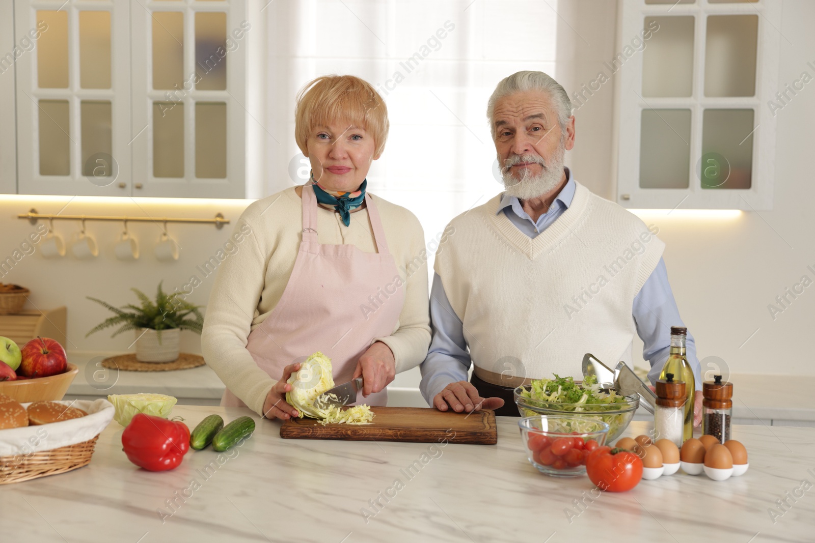 Photo of Senior couple cooking together at table in kitchen