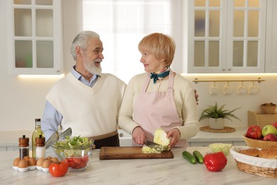 Photo of Senior couple cooking together at table in kitchen