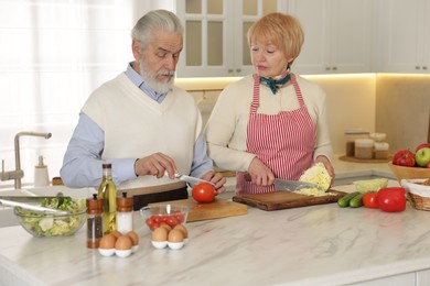 Photo of Senior couple cooking together at table in kitchen