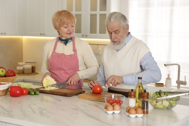 Senior couple cooking together at table in kitchen