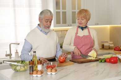 Senior couple cooking together at table in kitchen