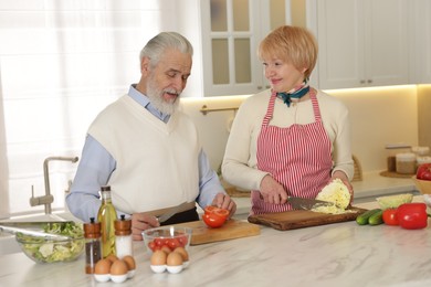 Senior couple cooking together at table in kitchen