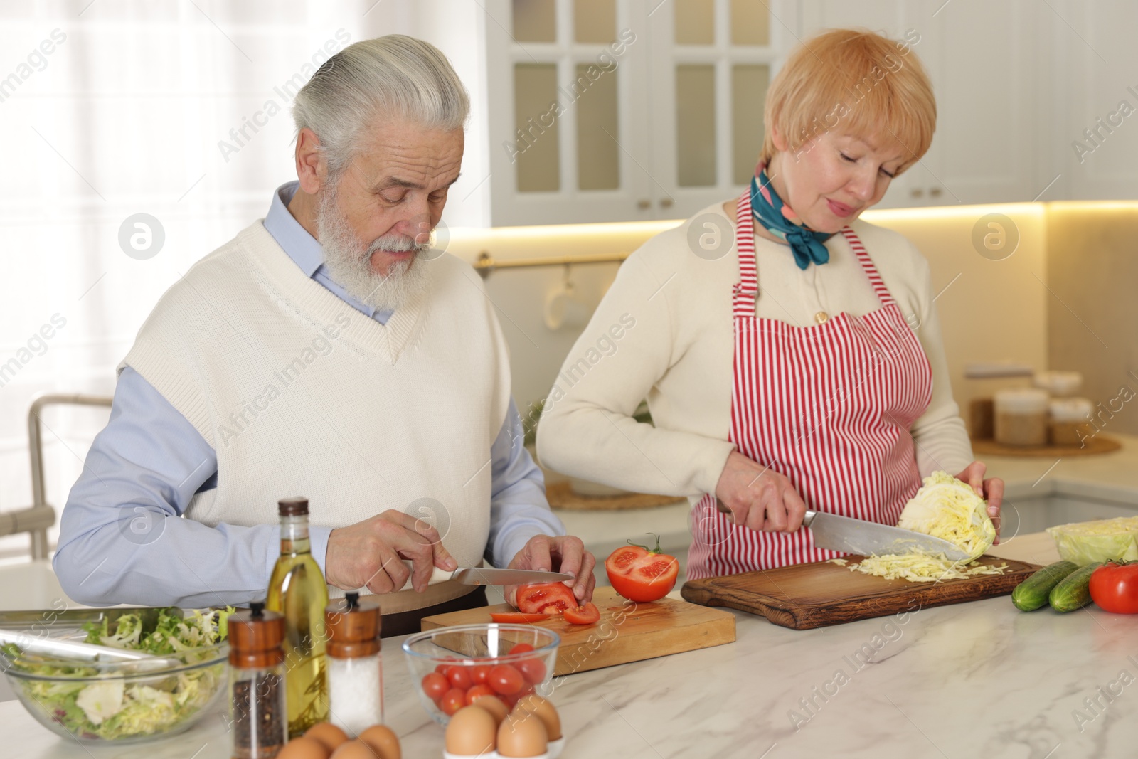 Photo of Senior couple cooking together at table in kitchen