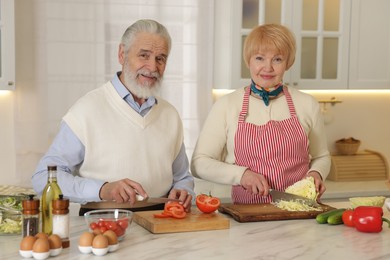 Photo of Senior couple cooking together at table in kitchen