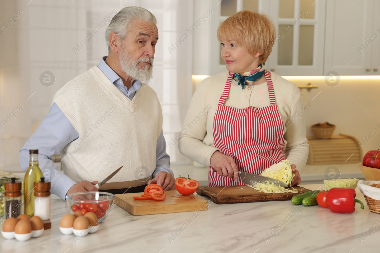 Photo of Senior couple cooking together at table in kitchen