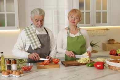 Senior couple cooking together at table in kitchen