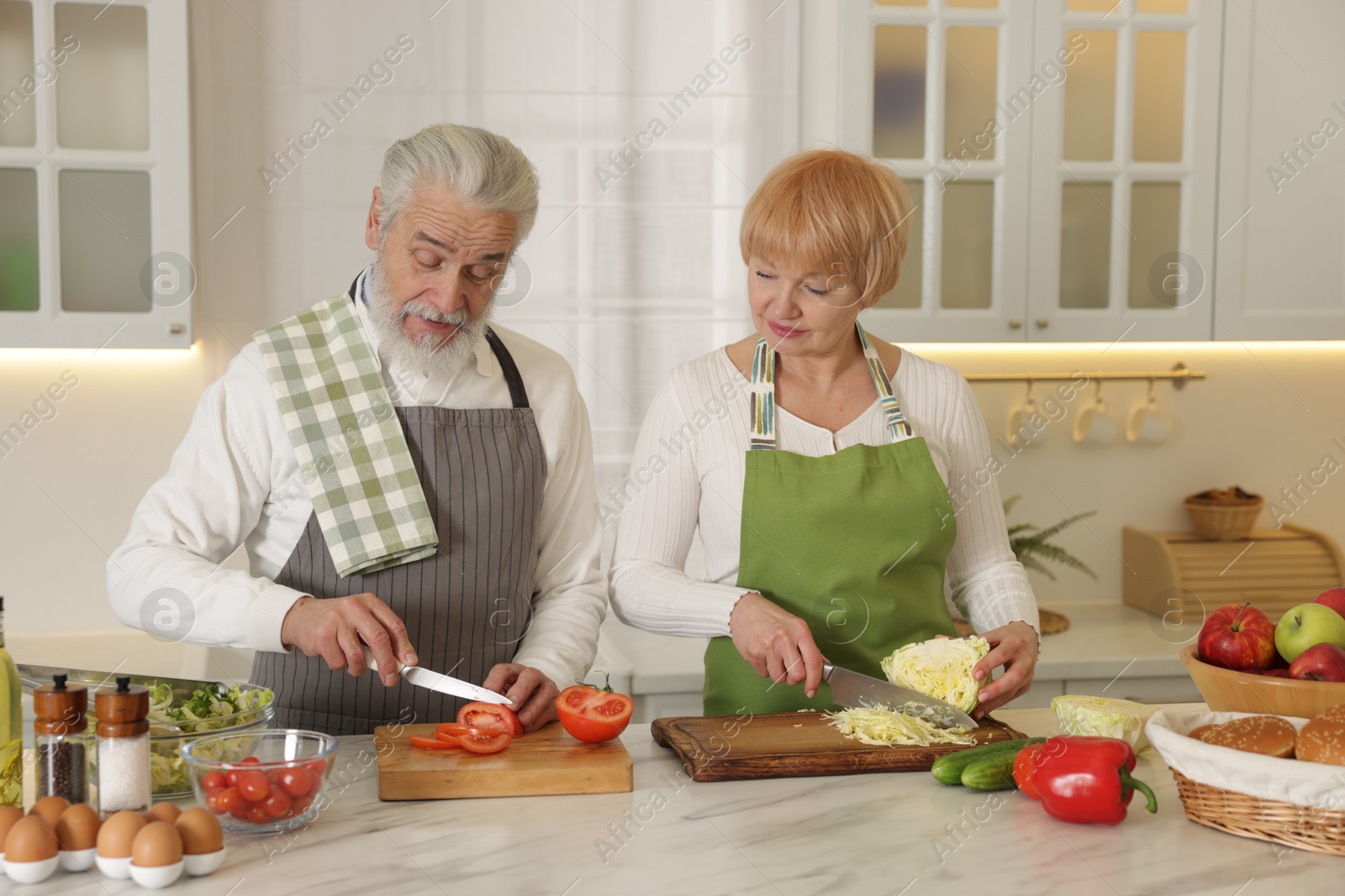 Photo of Senior couple cooking together at table in kitchen