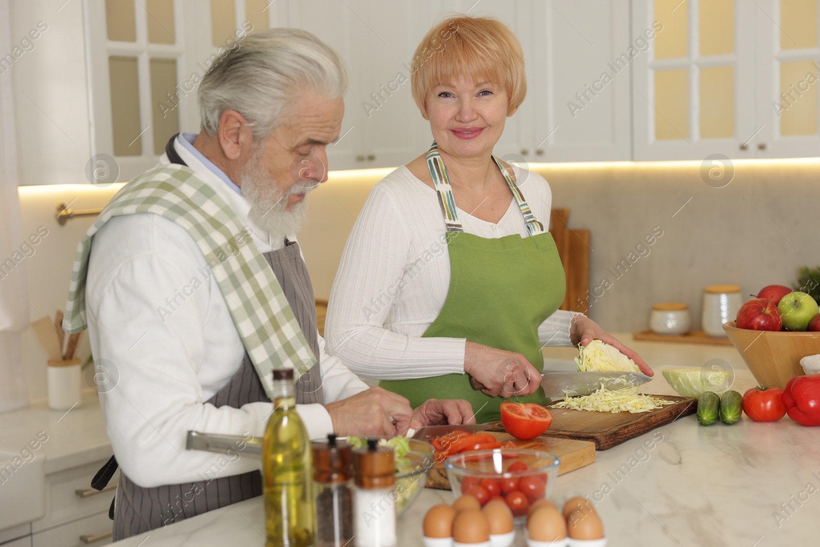 Photo of Senior couple cooking together at table in kitchen