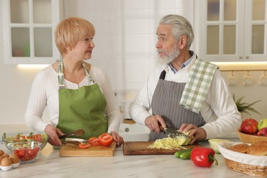 Photo of Senior couple cooking together at table in kitchen