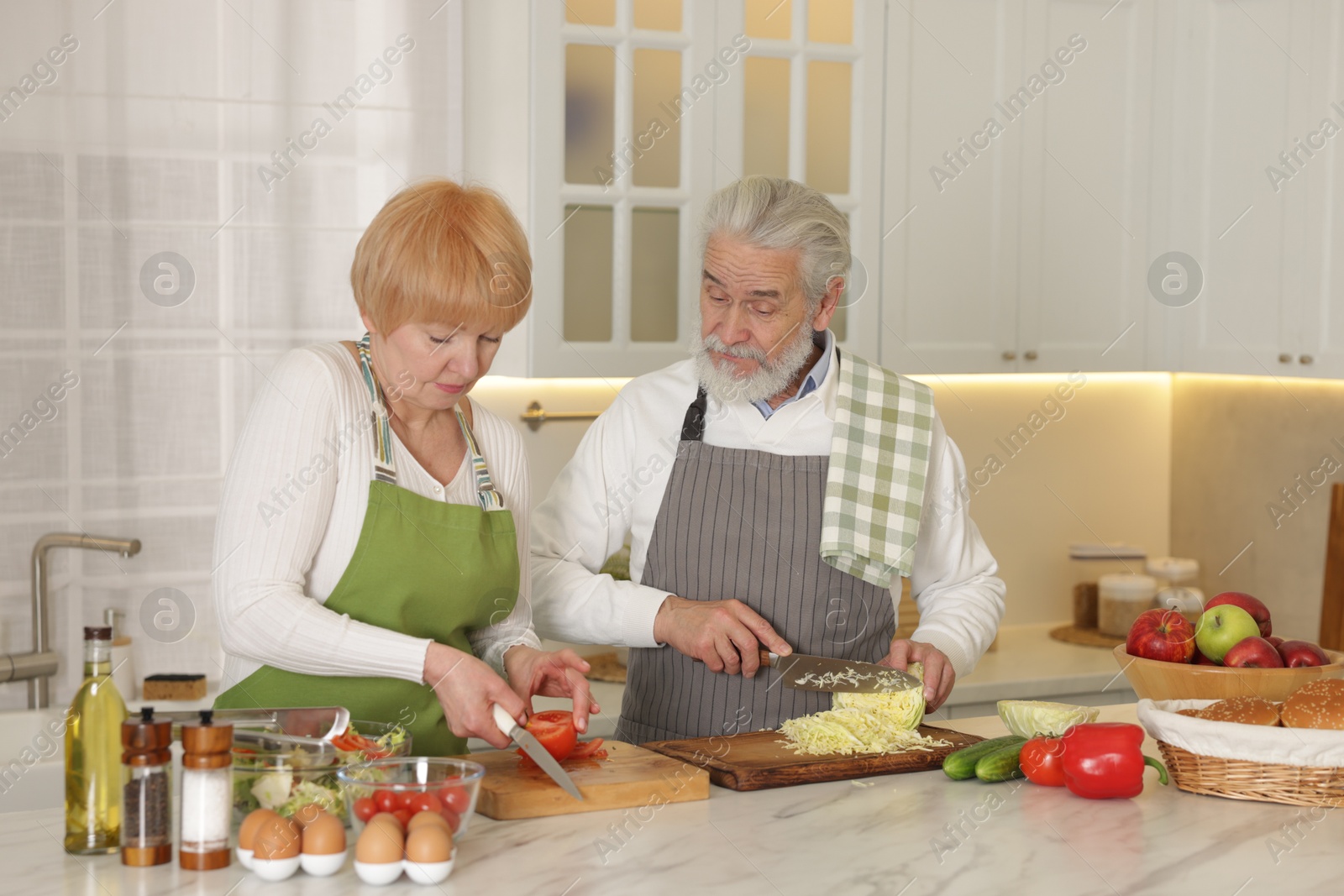 Photo of Senior couple cooking together at table in kitchen