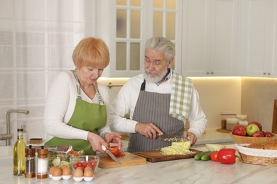 Senior couple cooking together at table in kitchen