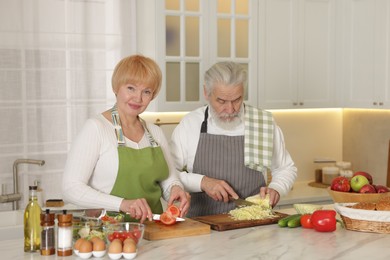 Senior couple cooking together at table in kitchen