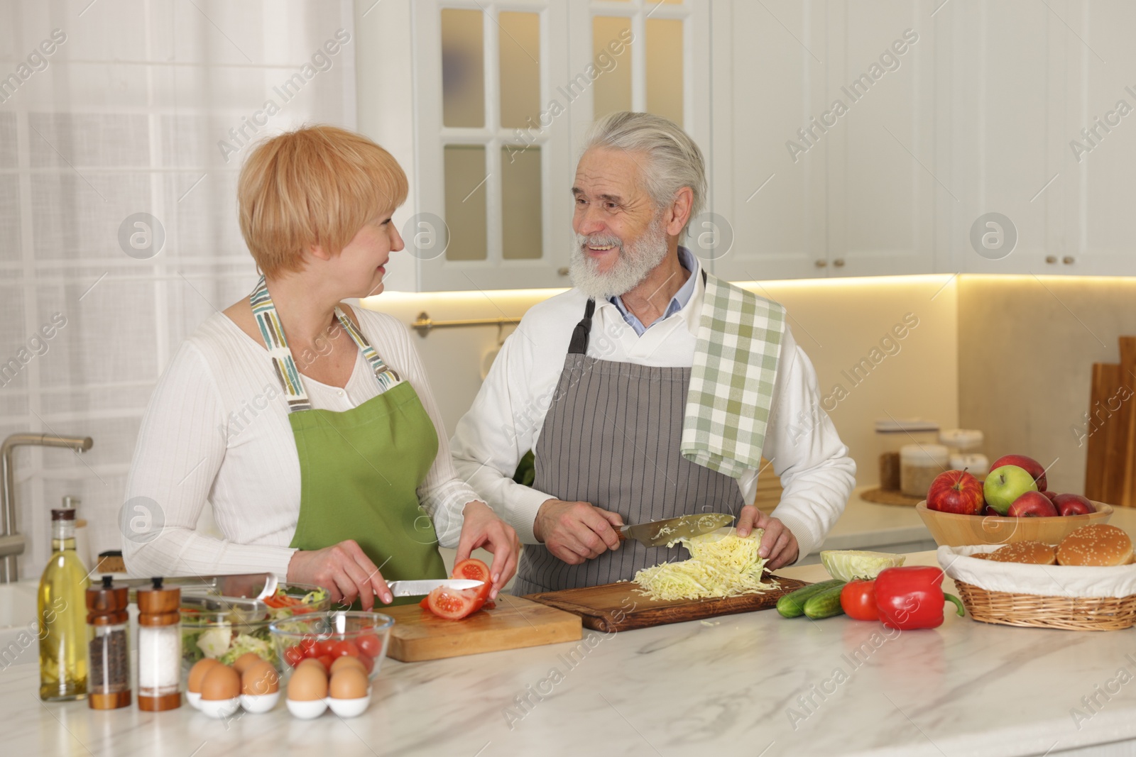 Photo of Senior couple cooking together at table in kitchen