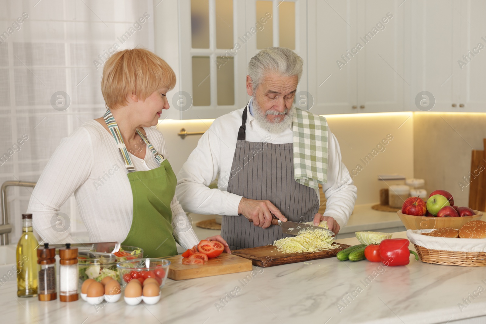 Photo of Senior couple cooking together at table in kitchen