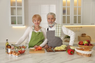 Senior couple cooking together at table in kitchen