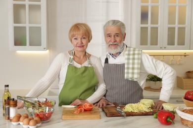 Photo of Senior couple cooking together at table in kitchen