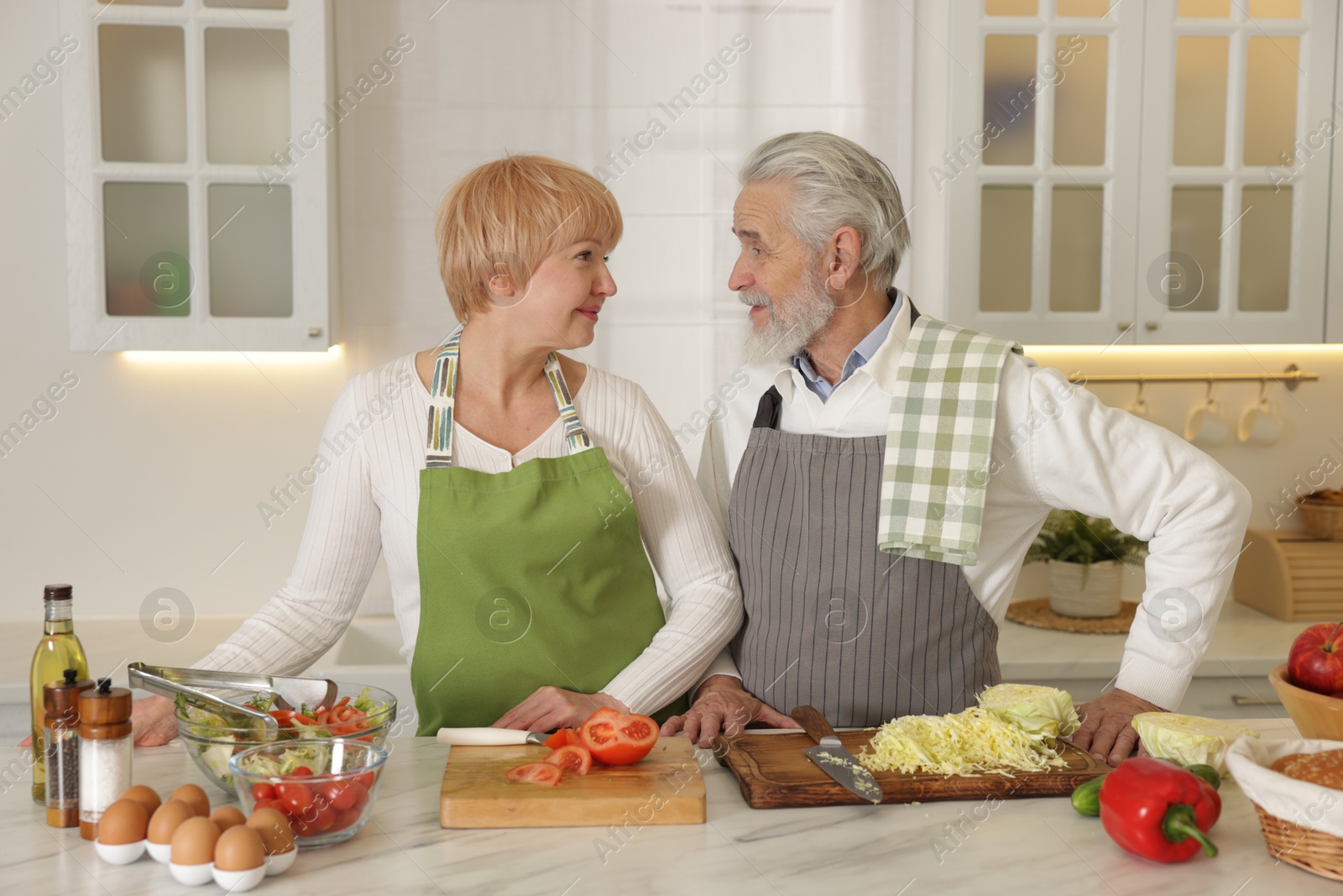 Photo of Senior couple cooking together at table in kitchen