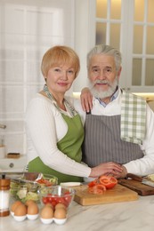 Photo of Senior couple cooking together at table in kitchen