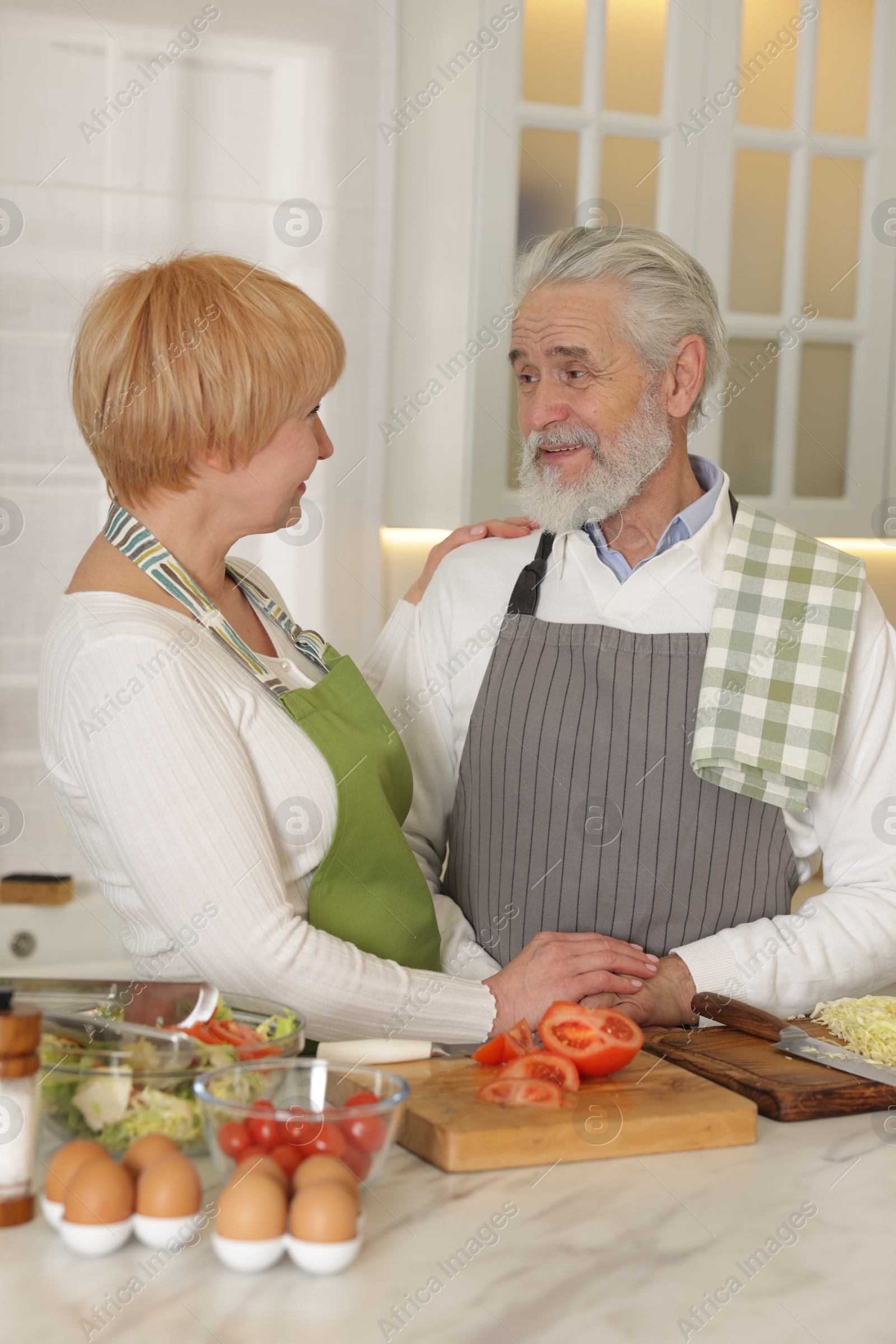 Photo of Senior couple cooking together at table in kitchen