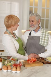 Photo of Senior couple cooking together at table in kitchen