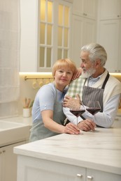 Senior couple with glasses of wine in kitchen