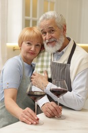 Senior couple with glasses of wine in kitchen