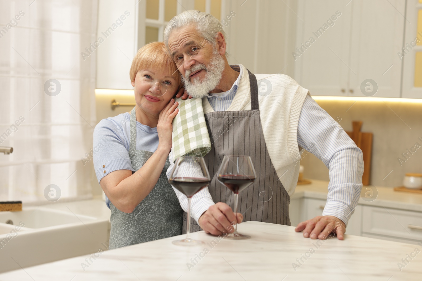 Photo of Senior couple with glasses of wine in kitchen