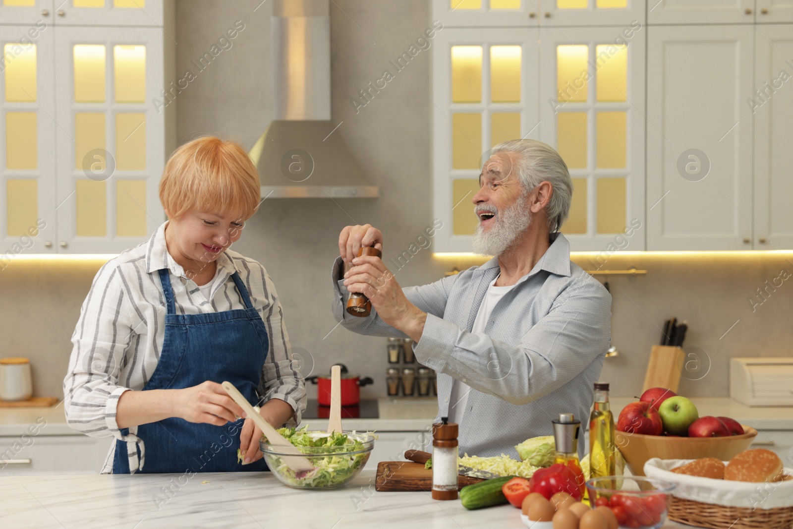 Photo of Senior couple cooking together at table in kitchen