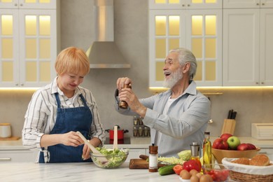 Photo of Senior couple cooking together at table in kitchen