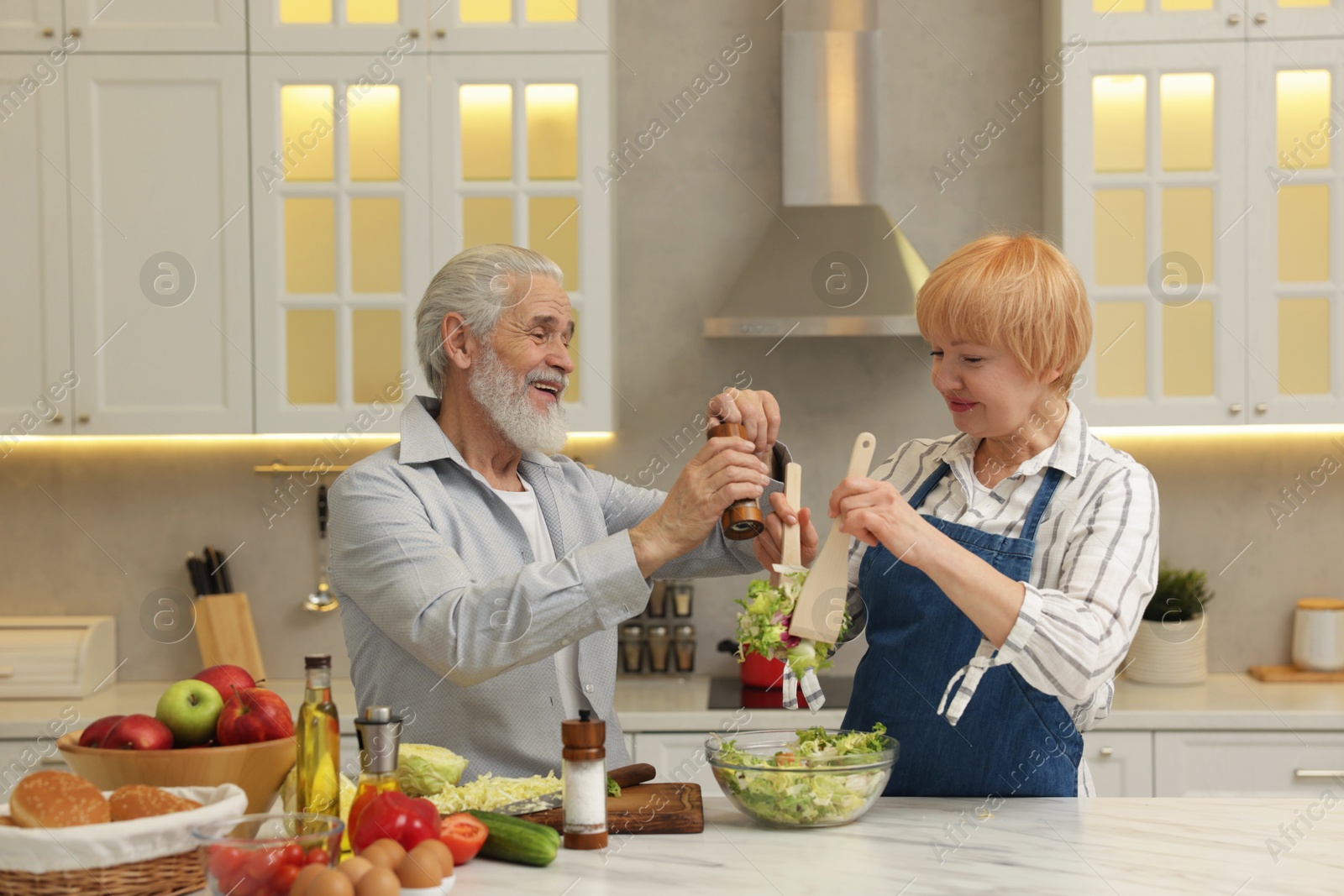 Photo of Senior couple cooking together at table in kitchen