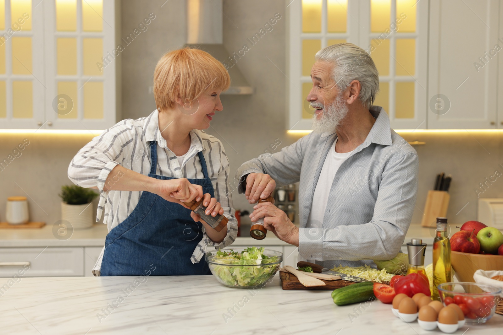 Photo of Senior couple cooking together at table in kitchen