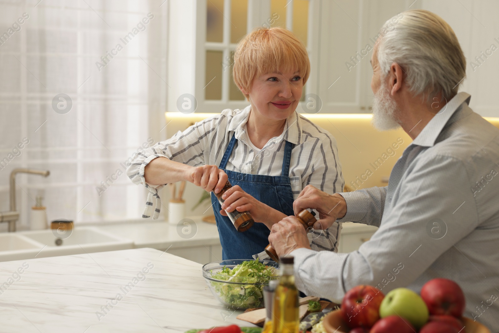 Photo of Senior couple cooking together at table in kitchen