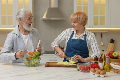 Photo of Senior couple cooking together at table in kitchen