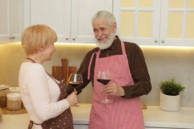 Photo of Senior couple with glasses of wine in kitchen