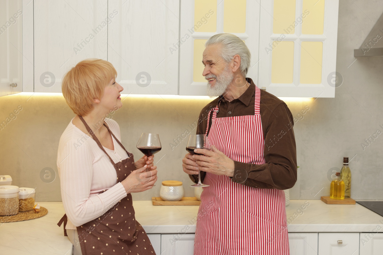 Photo of Senior couple with glasses of wine in kitchen