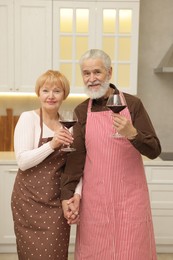 Photo of Senior couple with glasses of wine in kitchen