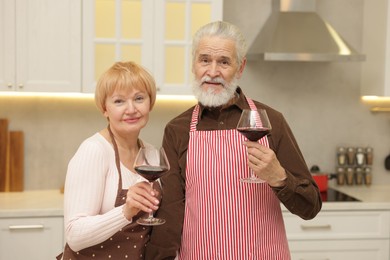 Photo of Senior couple with glasses of wine in kitchen