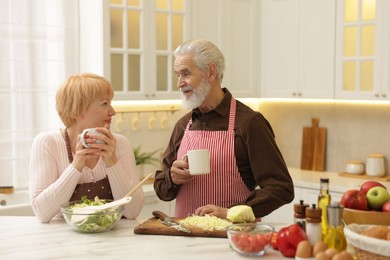 Photo of Senior couple having tea while cooking together in kitchen