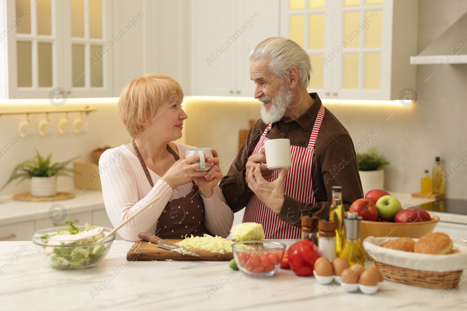 Photo of Senior couple having tea while cooking together in kitchen