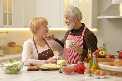 Photo of Senior couple having tea while cooking together in kitchen