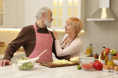 Senior couple cooking together at table in kitchen