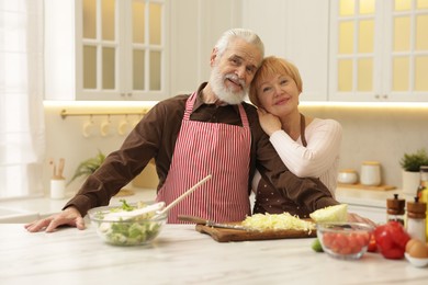 Senior couple cooking together at table in kitchen